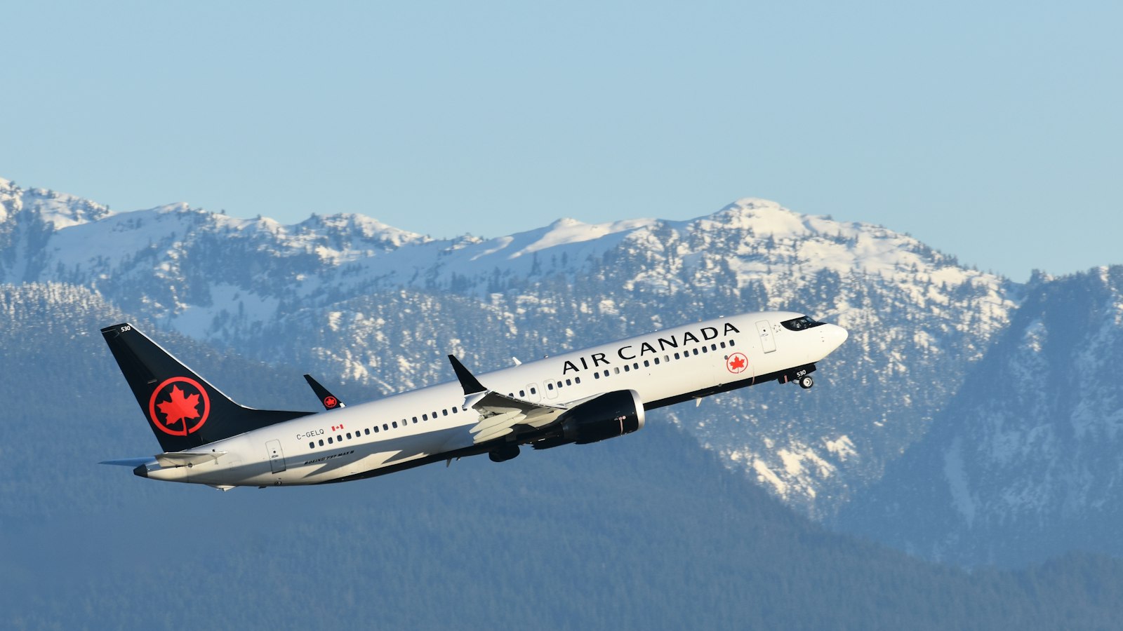 an air canada airplane flying over a mountain range