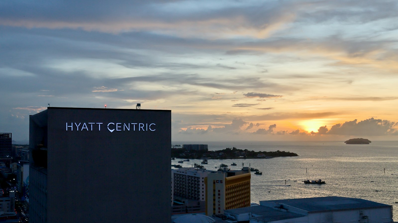 Hyatt centric building overlooks a coastal city at sunset