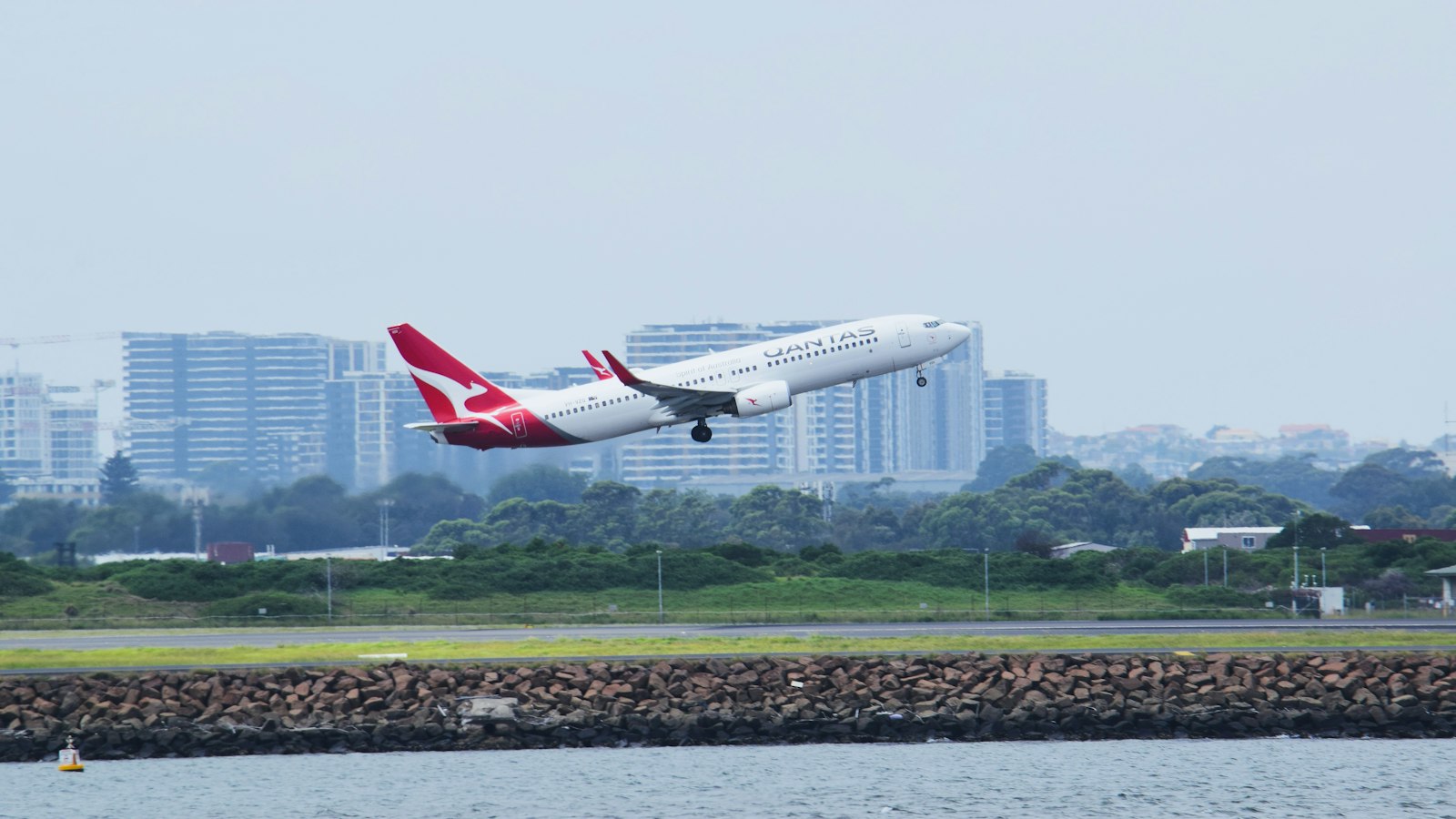a large jetliner flying over a body of water