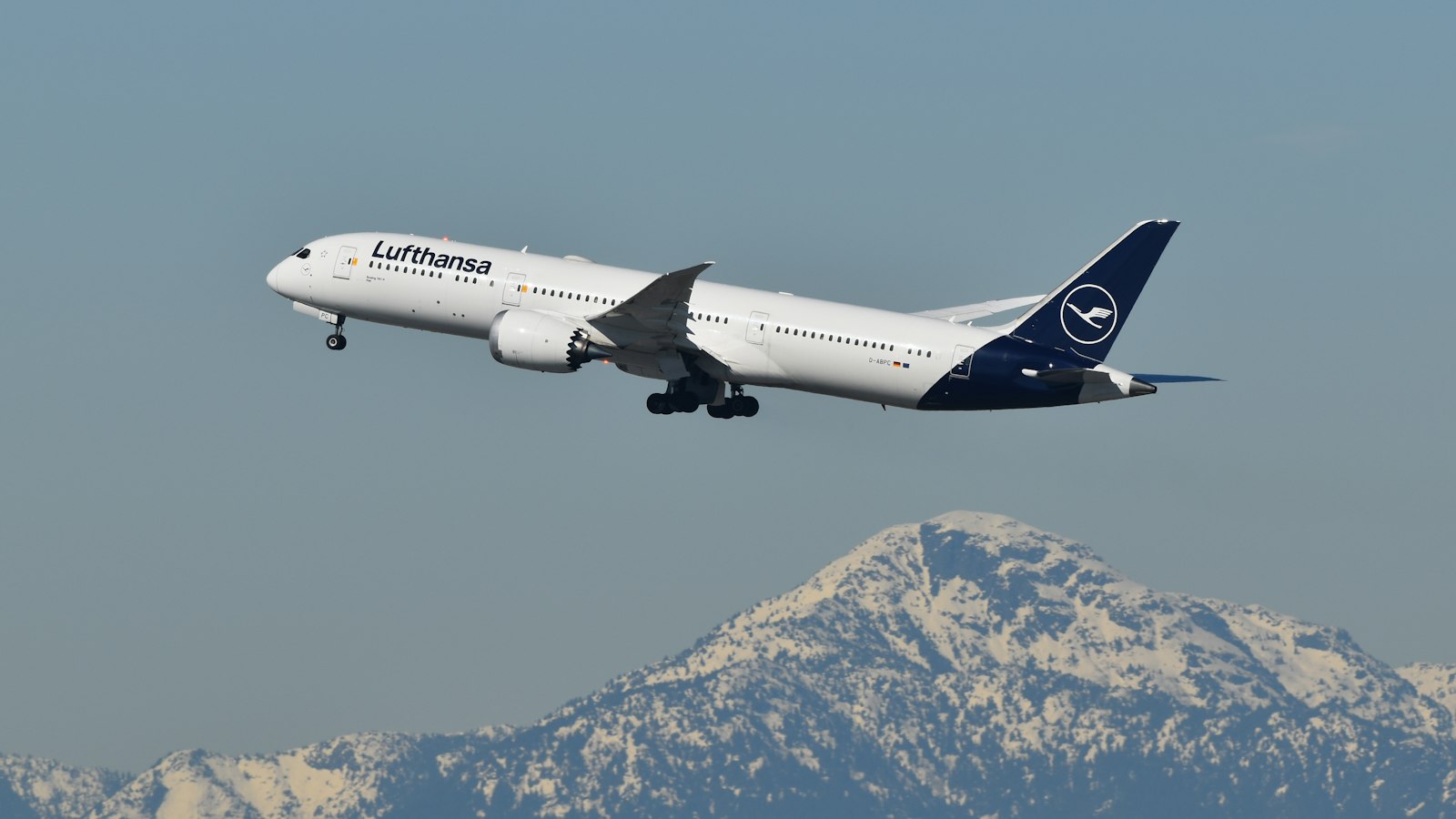 A large jetliner flying over a mountain range